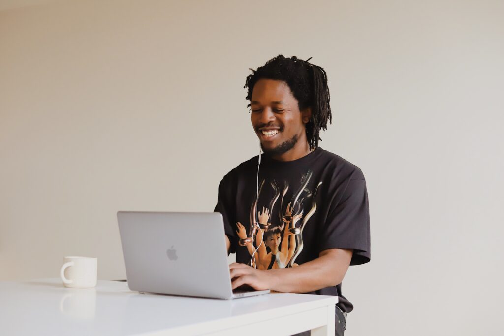 Image of an African-American man smiling during an online therapy session from a cafe in Georgia. With online counseling, you can meet with an online therapist from a cafe, at work, or at home.