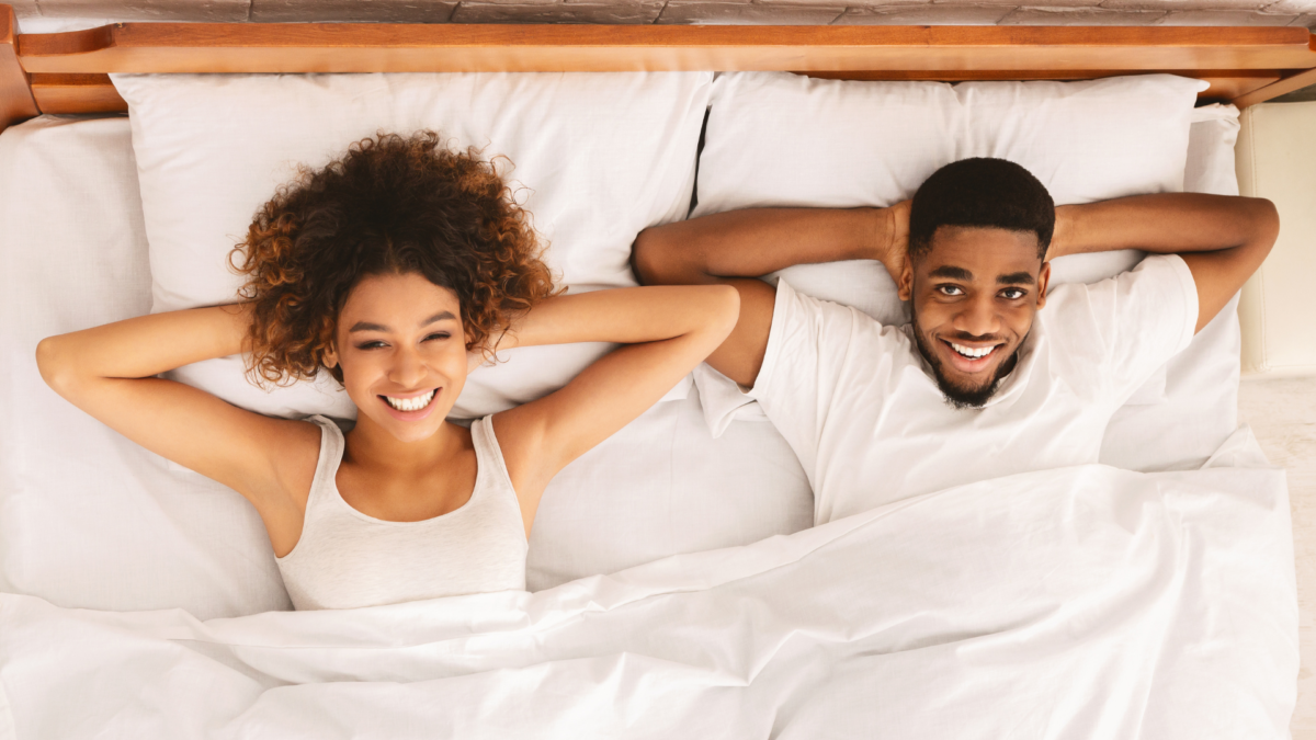 Image of a black couple laying in bed together smiling. This type of connection can be had after starting black couples counseling and black marriage counseling in Atlanta, GA. Start repairing your relationship with support from an Atlanta black couples therapist.