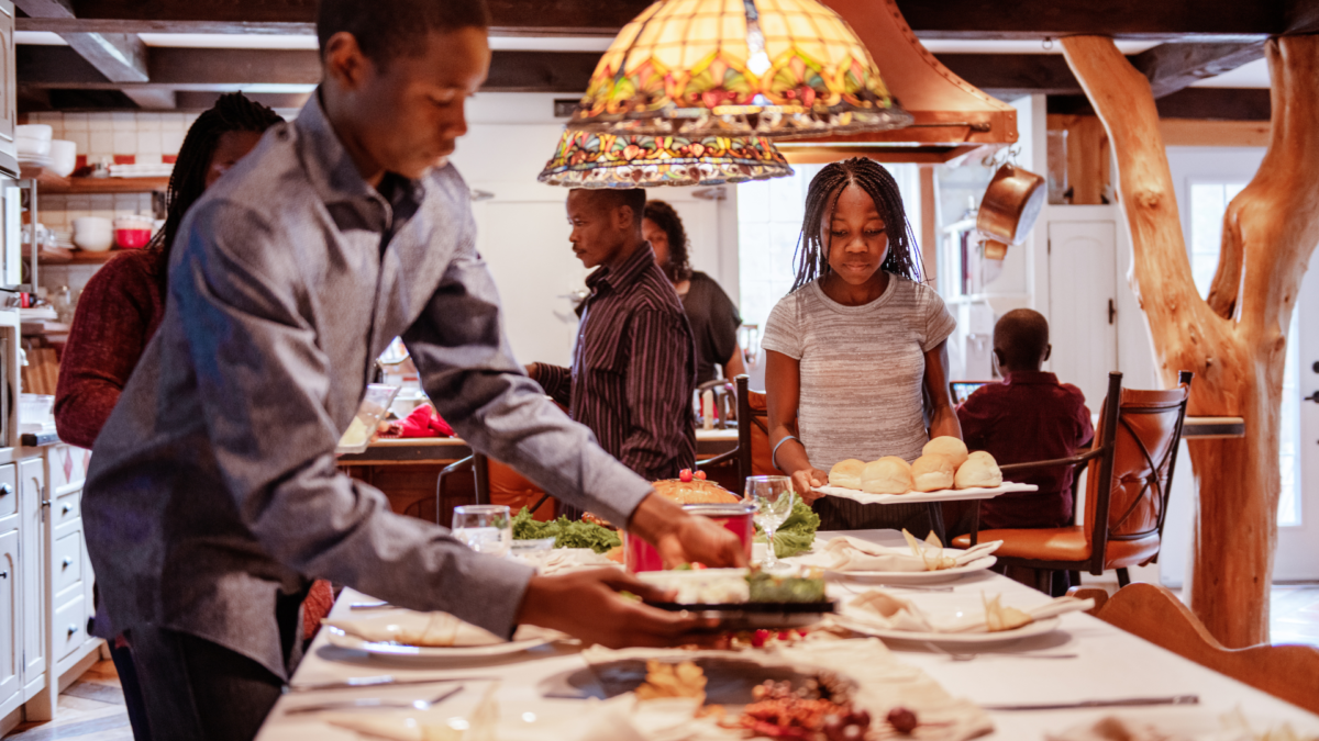 Image of a black family setting a table together during the holidays. Showing that support from family and an Atlanta therapist can help support mental health in the black community. For additional support start therapy for black people in Atlanta.