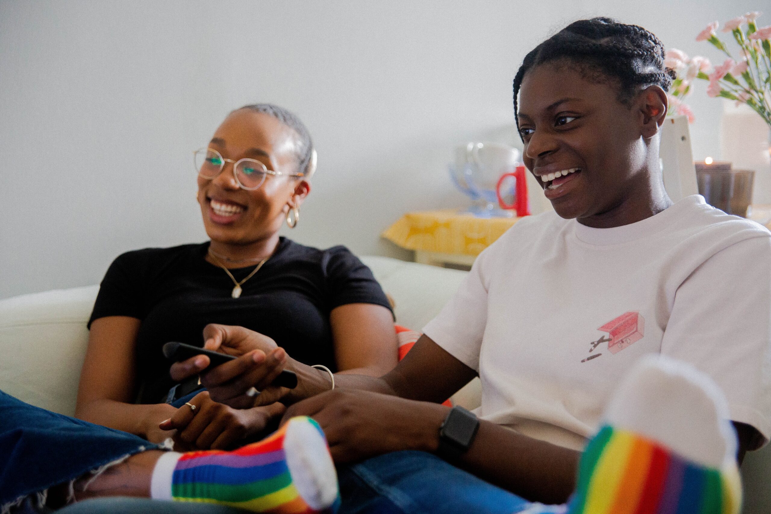 Image of a couple sitting and watching TV together while laughing. Showing that by starting black couples counseling you can end that disconnect. The skills learned in black couples therapy in Atlanta, GA can make the time with your partner more like this.