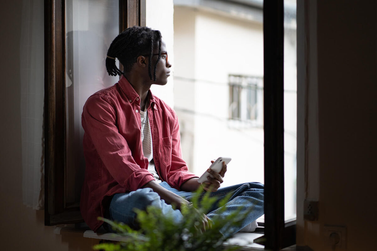 Image of an African American man looking out of a window. Representing the need for therapy for black men to support mental health in the black community in Atlanta, GA. Where you offer you option to find a "Black therapist near me" from anywhere in Atlanta.