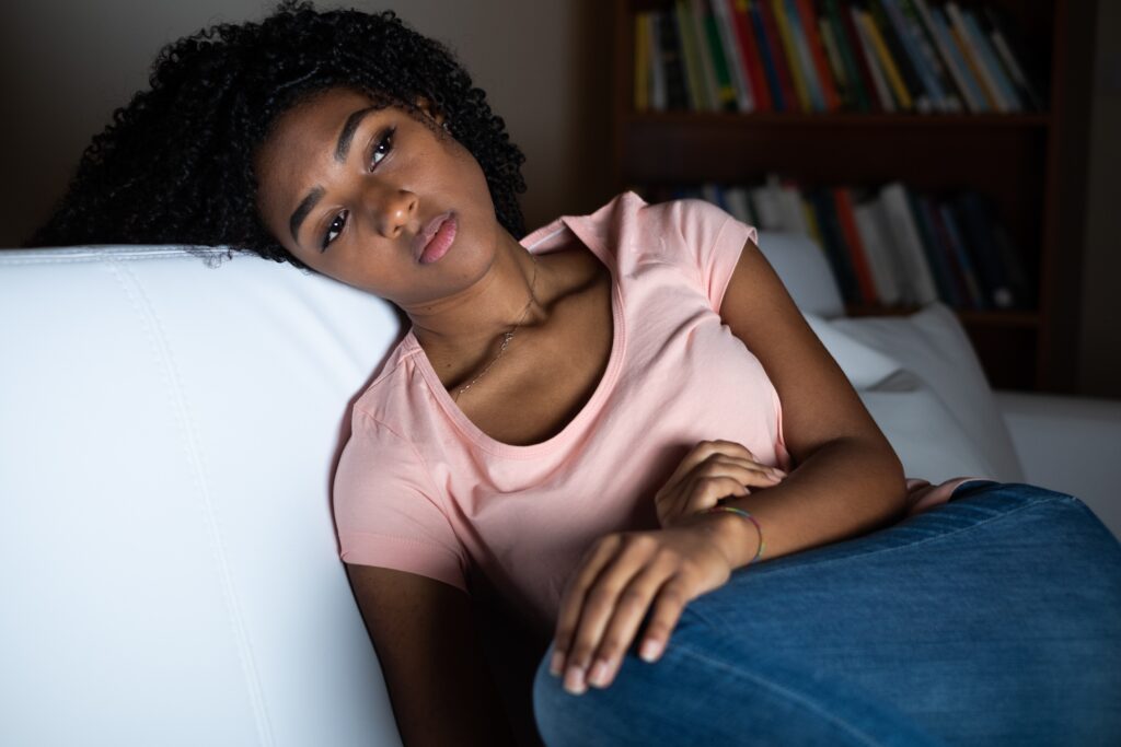 Image of a Black woman showing grief symptoms while laying down. Representing someone that is in need of grief and loss counseling in Atlanta, GA. Where a grief specialist can give guidance in grief counseling.