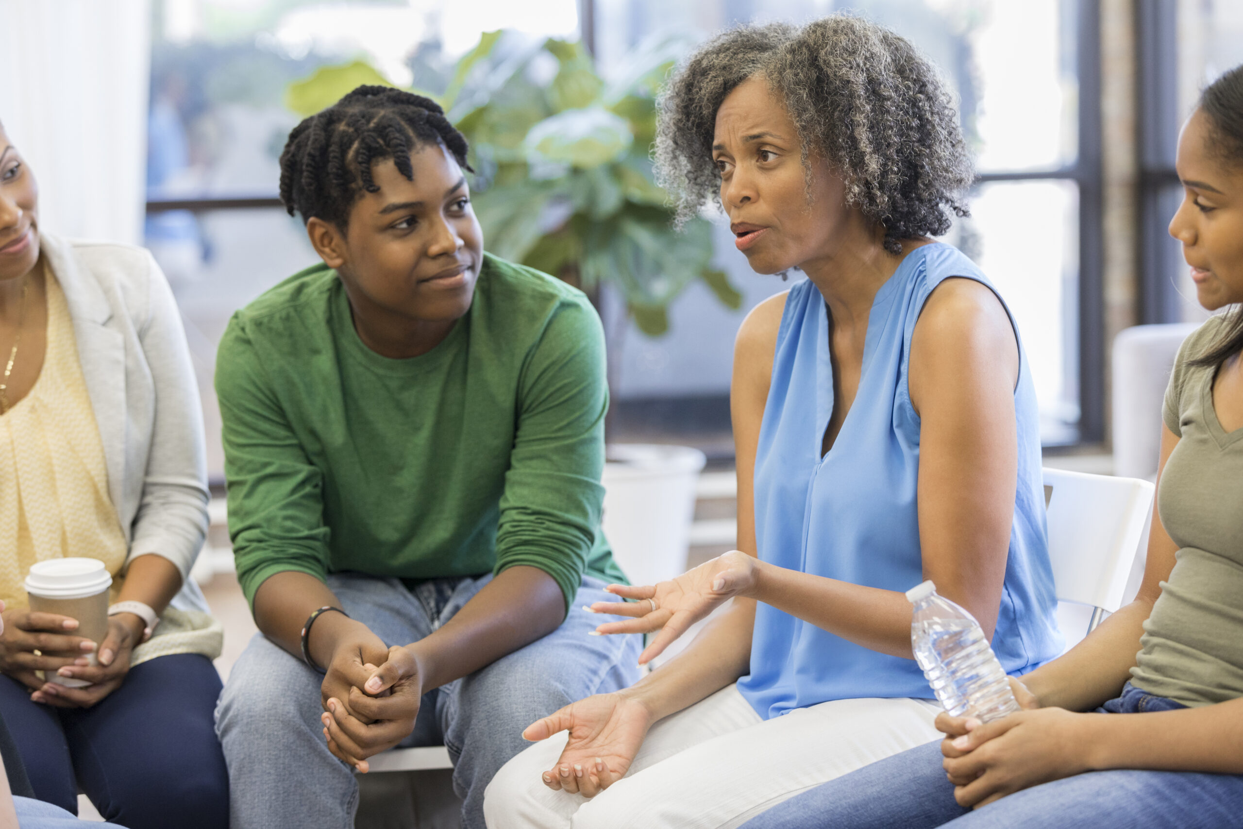 Image of a Black group therapist in a blue shirt meeting with other women. Showing what group therapy can look like in Atlanta, GA. You can even get specific anxiety group therapy in Atlanta.