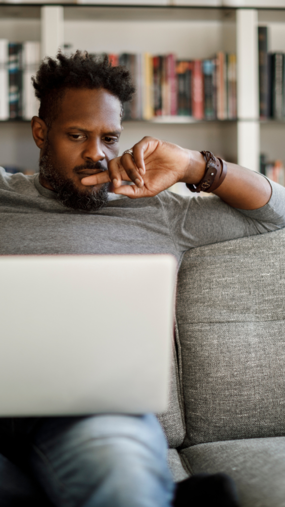 Image of a Black man looking at a computer & procrastinating. Representing someone who could benefit from seeing an Atlanta therapist for their anxiety symptoms. Anxiety therapy can provide you with the help you need.