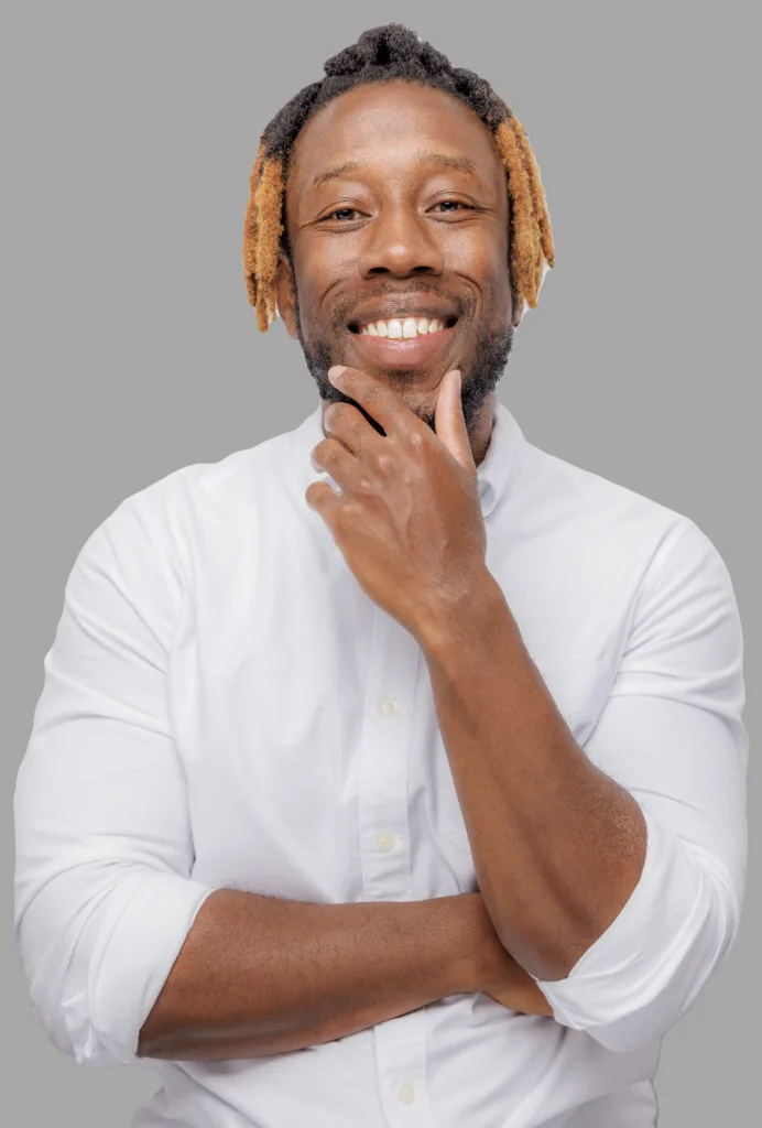 Image of Black male therapist with bright smile and hand on chin in a white shirt. Representing Atlanta therapist providing in person and online therapy services.