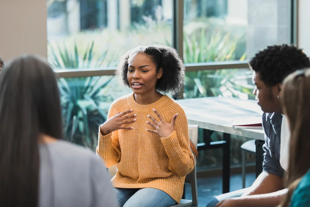 During a group therapy session in Atlanta, GA, a Black woman in yellow sweater discusses her emotions.