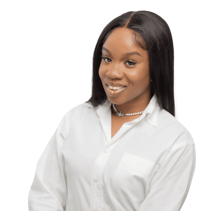 Smiling Black woman EMDR therapist with natural hair, wearing a white top, in her Atlanta, Georgia office, specializing in trauma therapy and emotional support.